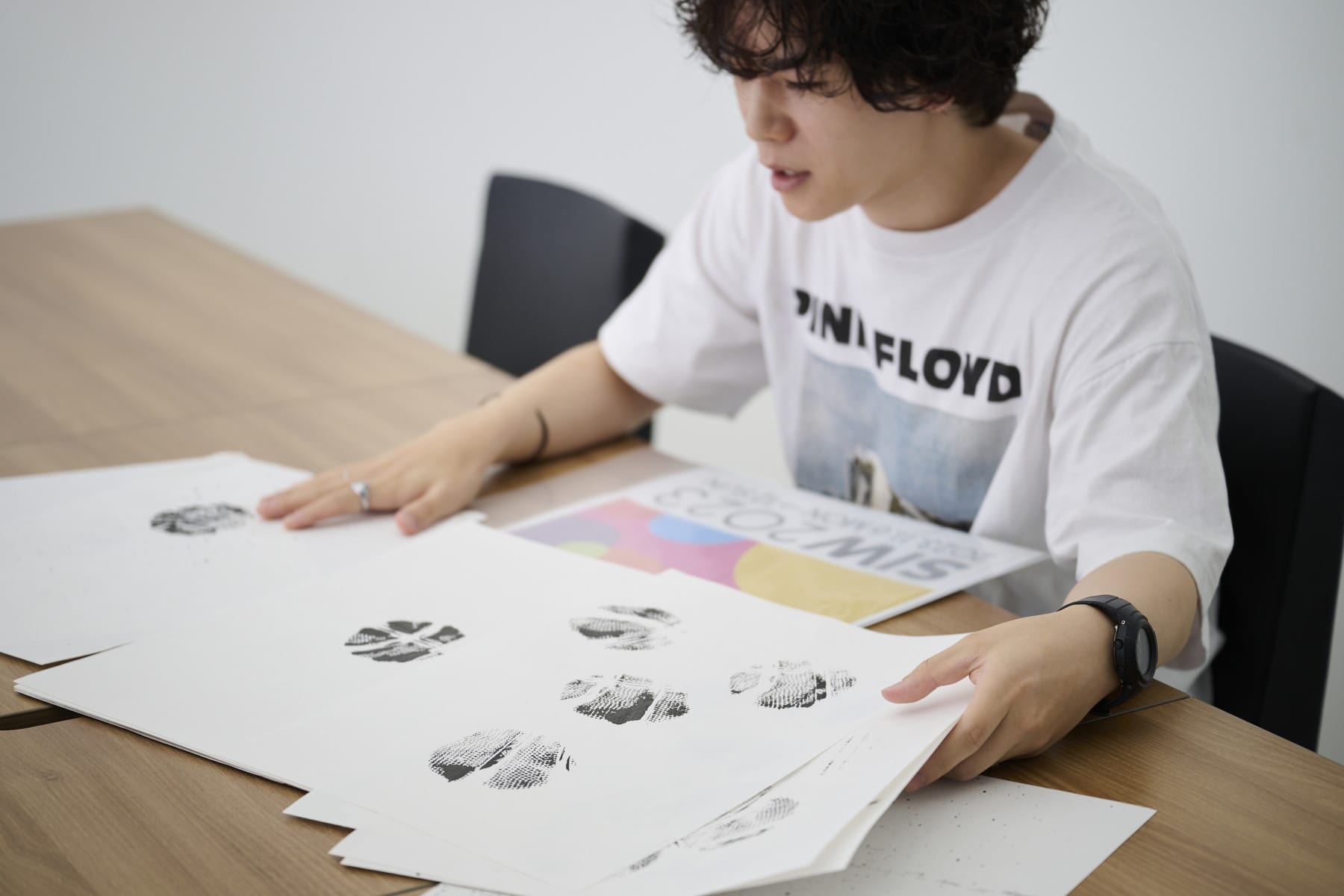 さまざまなパターンの墨のシルエットがついた画用紙を広げる大橋さん